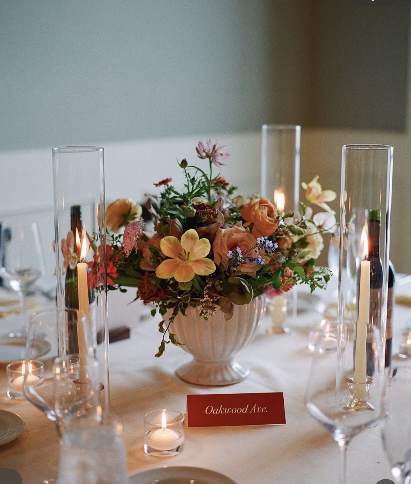 Individual autumn-toned arrangement of yellow tulips and orange ranunculus in a white urn