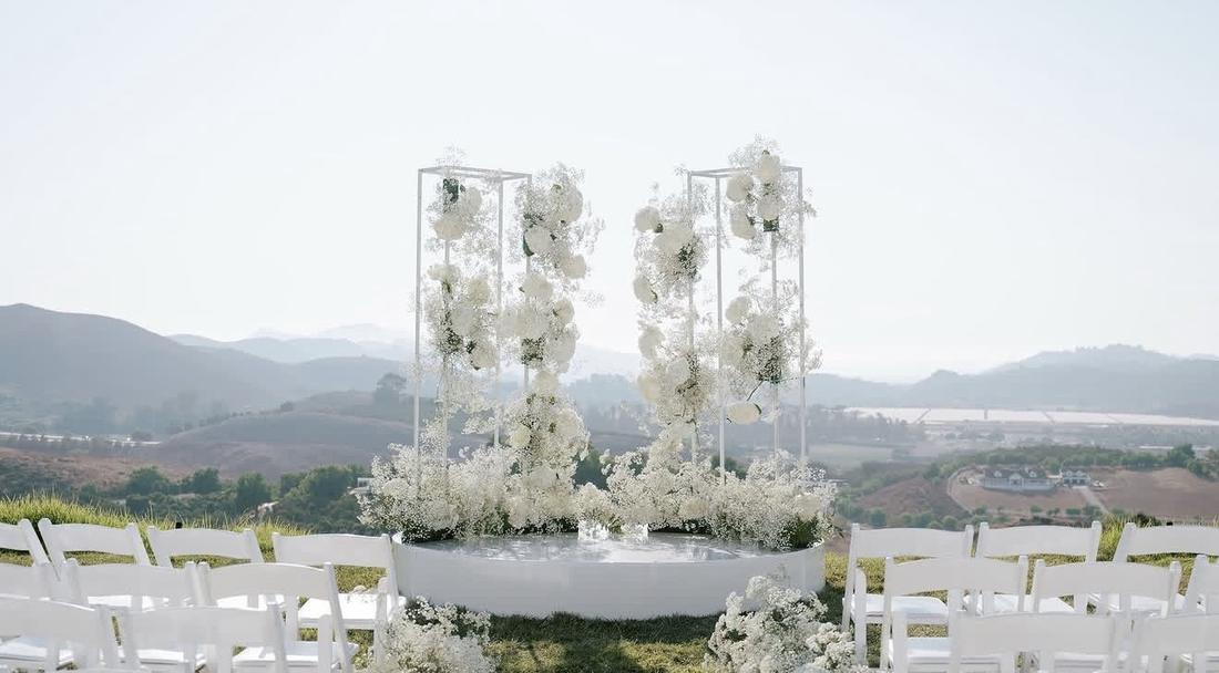 Two floral towers of white hydrangea and baby's breath above a reflecting pool