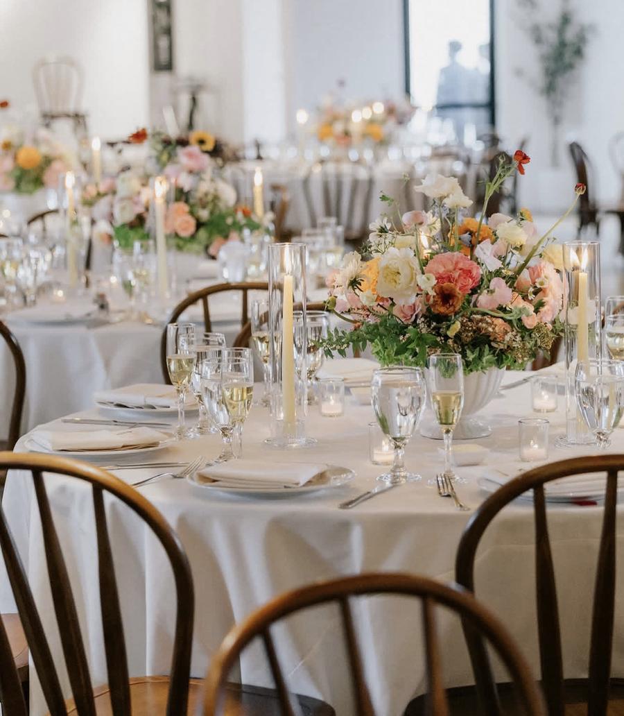 Round reception tables with garden-style centerpieces and taper candles